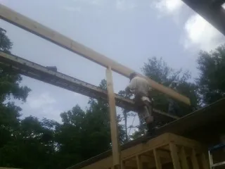 Carpenter setting a ridge beam over a new addition frame — Ice Dam Removal by Roofing Brothers in Friesland