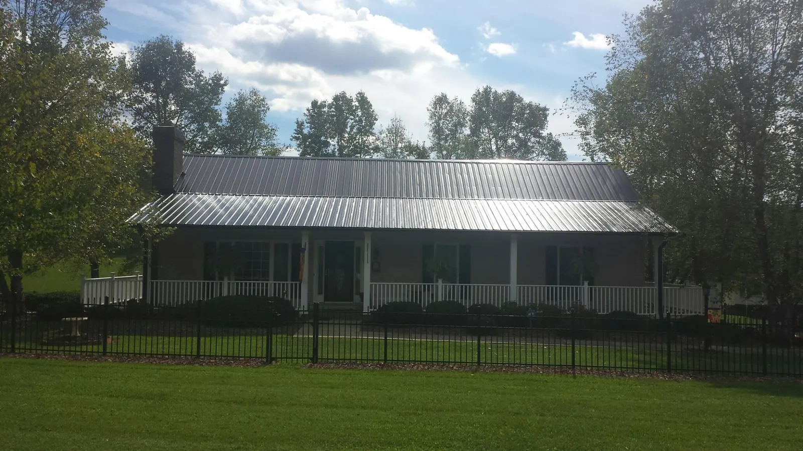 Gray metal roof on a brick ranch with a full width front porch — Gutter Guard Installation work by our crew in Friesland