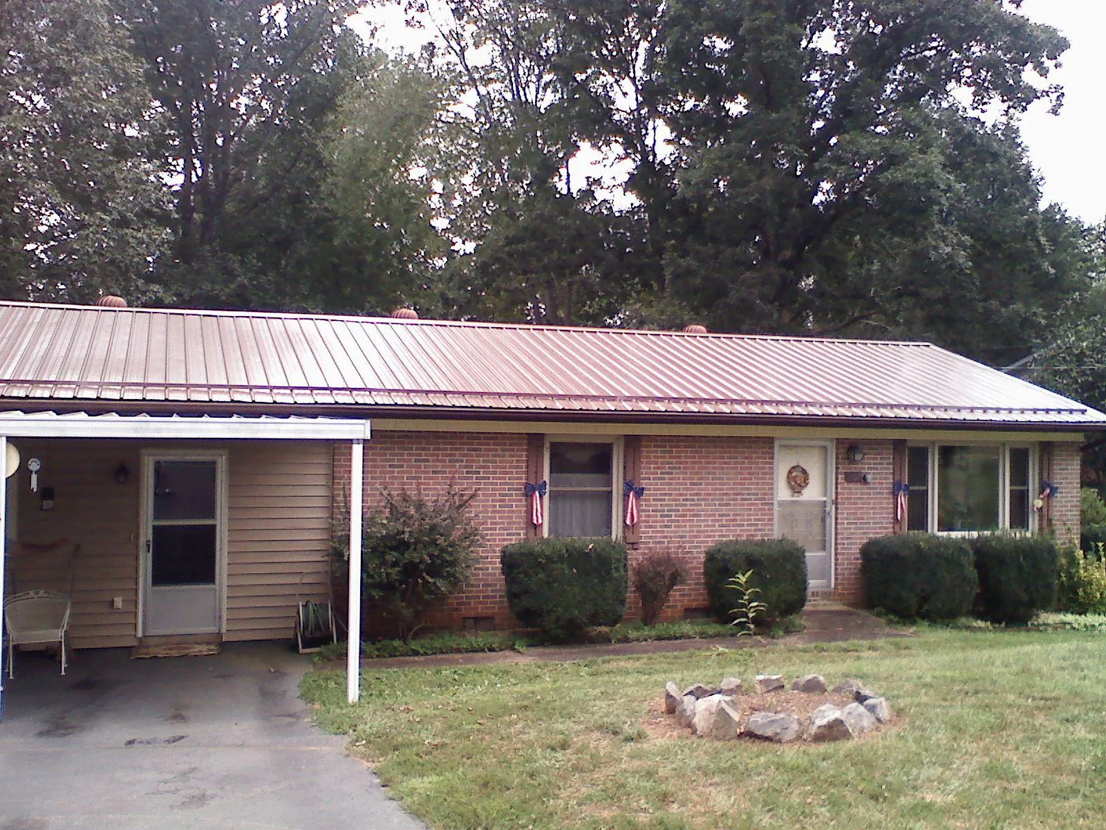 Bronze metal roof and carport on a brick ranch home — Roof Repair work by our crew in Friesland