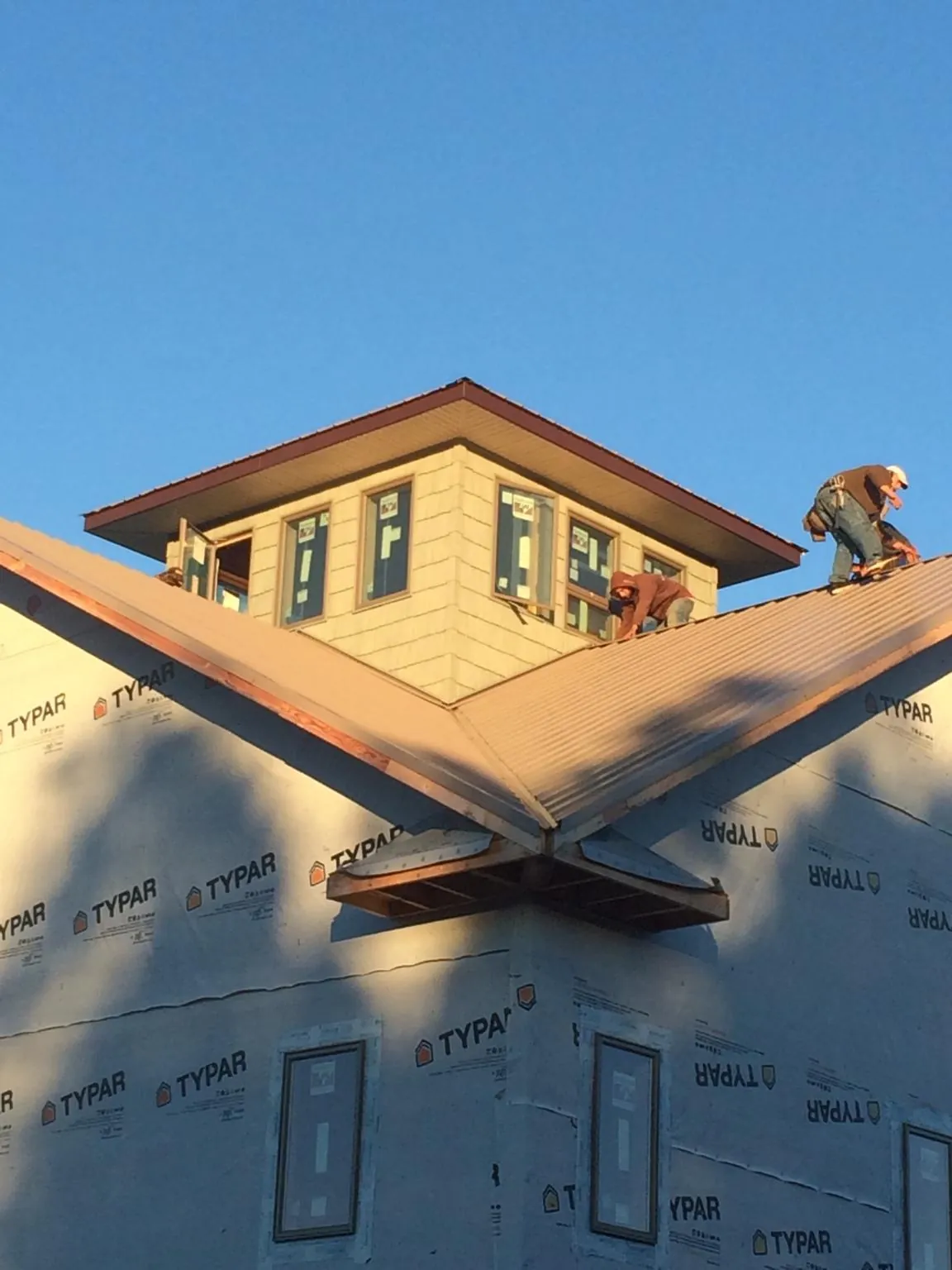 Roofers working around a rooftop cupola on a new metal roof at sunset — Roof Waterproofing in Friesland by Roofing Brothers